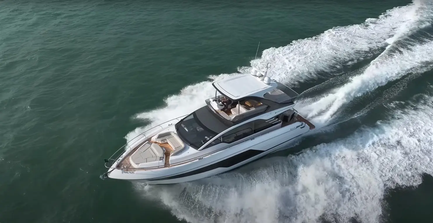 Luxury motor yacht speeding across the turquoise water, leaving a wake behind, showcasing its sleek design and spacious deck.